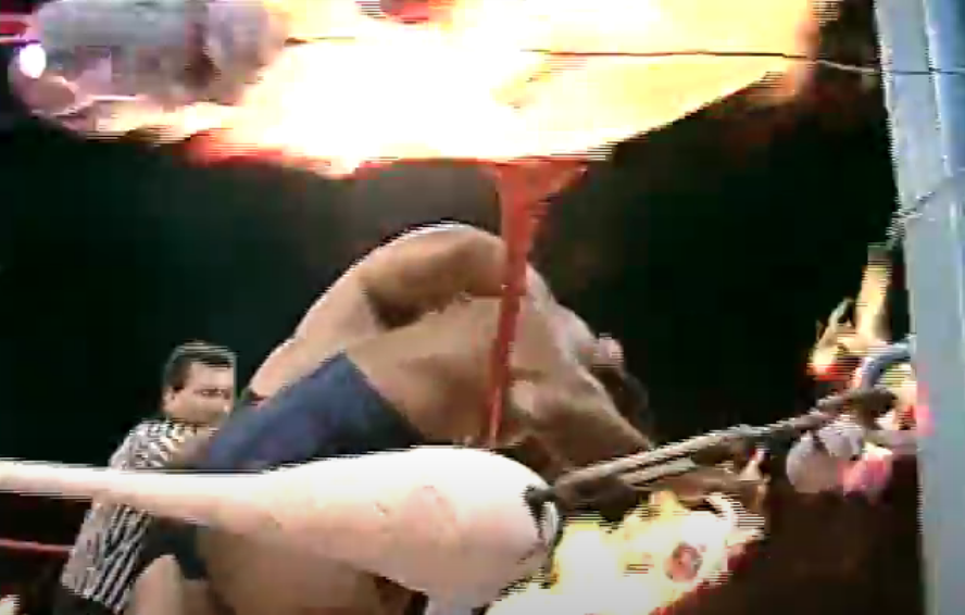 Hercules Ayala tries to push Carlos Colon's face into a burning rag.