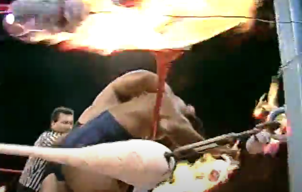 Hercules Ayala tries to push Carlos Colon's face into a burning rag.